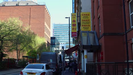 Daytime-view-of-bustling-Manchester-street-with-Chinese-signage,-hinting-at-a-cultural-quarter