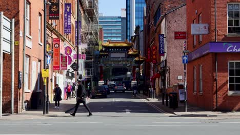 Bright-day-view-of-Manchester's-Chinatown-with-traditional-Chinese-arch,-pedestrians-and-urban-storefronts