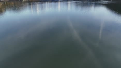 Ruhiger-See,-Der-Eine-Brücke-In-Der-Nähe-Von-Steinbach-Spiegelt,-Mit-Schneebedeckten-Bergen-Im-Hintergrund,-Ruhige-Szene,-Luftaufnahme