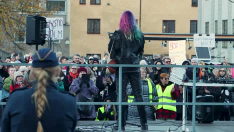Activist-Linnea-Claeson-at-women's-rights-rally-in-Stockholm,-viewed-from-behind,-crowd-with-banners