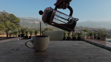 Coffee-Pouring-from-French-Press-with-Scenery,-Mountains,-Landscape-in-Background,-Black-Coffee,-Espresso-Coffee,-Holiday,-Air-BNB,-Vacation,-in-Garden-Coffeee