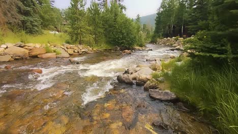 Mountain-stream-fresh-water-flowing-with-rocks-and-greenery