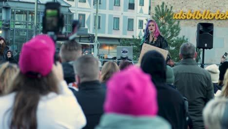 Woman-activist-Linnea-Claeson-speaking-at-rally-in-Stockholm,-vibrant-hair,-crowd-listening,-urban-backdrop,-daylight