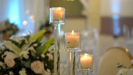 Wedding-room-decorated-with-centerpieces-of-white-roses-and-small-candelabras-with-lit-candles