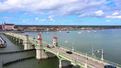4k-Still-Aerial-shot-of-traffic-passing-over-The-Bridge-of-Lions,-facing-the-Spanish-Fort,-Castillo-de-San-Marcos-National-Monument-with-blue-skies-and-intermittent-clouds