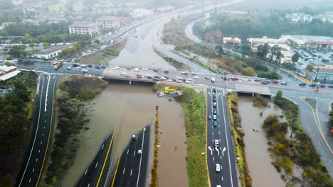 Muddy-flooded-water-pools-and-cuts-off-access-on-highway-causing-traffic-to-backup,-panoramic-aerial-orbit