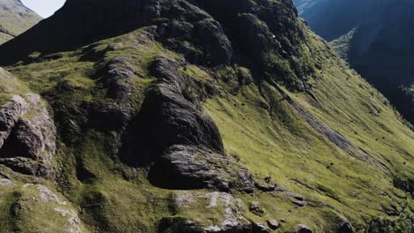 Drone-shot-tilting-up-to-reveal-a-tall-peak-in-Glenco-Valley,-Scotland