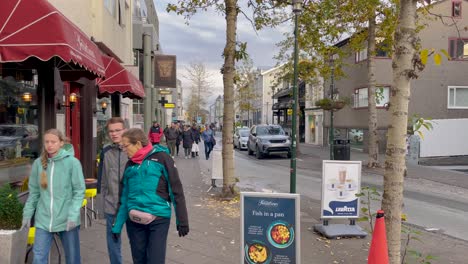 Paseo-Informal-Por-Una-Bulliciosa-Calle-De-Reykjavik,-Peatones-Con-Ropa-Abrigada,-Día-Nublado,-Escena-Urbana