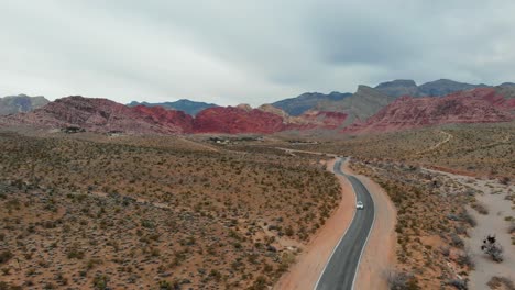 Aerial-drone-shot-of-a-desert-road-with-scenic-mountains-in-the-background