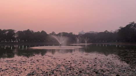 Static-shot-of-sunset-at-Rabindra-Sarobar-lake-with-beautiful-fountains-in-Kolkata,-India