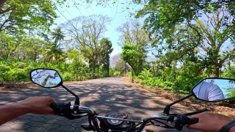 A-Man's-POV-riding-a-motorbike-on-a-clear-and-sunny-day,-through-a-jungle-road-on-Ometepe-island,-Nicaragua