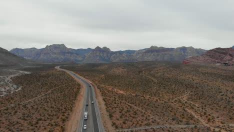 Aerial-drone-shot-of-a-desert-highway-with-mountains-in-the-background