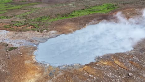 An-aerial-drone-view-with-a-quick-movement,-then-fixed-on-Engjahver's-steam-lake-on-the-Reykjanes-Peninsula-in-Iceland