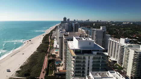 drone-video-of-a-bright-sunny-day-at-the-beach-overlooking-the-beach-and-luxury-condominium-apartment-buildings-by-the-ocean