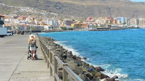 Mother-with-a-stroller-walking-on-a-pier-on-vacation-in-Tenerife,-Spain