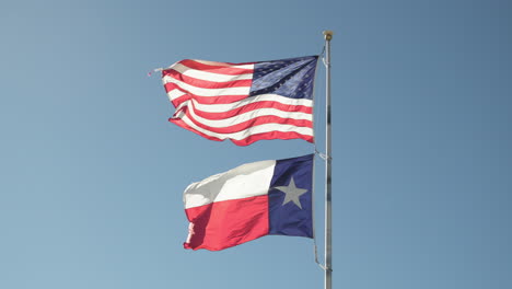 Die-Amerikanischen-USA-Starten-Und-Streifen-Die-Flagge-Mit-Der-Texanischen-Flagge-Im-Wind-An-Einem-Fahnenmast