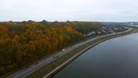 Drone-shot-of-cars-driving-on-a-road-near-Neman-river-in-Kaunas,-Lithuania