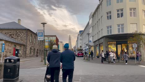Quiet-street-in-Reykjavik-with-pedestrians-and-iconic-Hallgrimskirkja-in-background,-cloudy-day