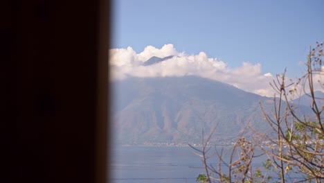 Viewing-the-Lake-Aititlan-volcano-from-an-apartment-window,-through-the-tress-in-Guatemala,-Slow-motion