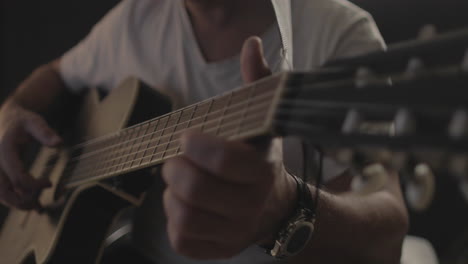 Mann-Spielt-Akustikgitarre-Mit-Schwarzem-Hintergrund-Und-Weichem,-Warmem-Licht
