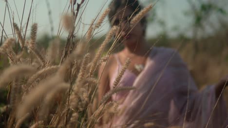 Woman-in-pink-dress-enjoying-serene-moment-in-golden-wheat-field-at-sunset,-soft-focus