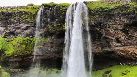 Tourists-gathered-under-Seljalandsfoss-Icelandic-waterfall-behind-powerful-cascading-downpour