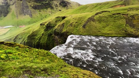 Slow-push-in-to-Skogafoss-waterfall-flowing-over-top-of-Icelandic-cliff-edge-from-Skoga-river
