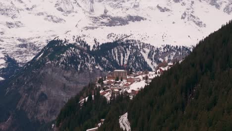 Aerial-view-of-Switzerland-highland-village-near-mountain-edge,-winter-season
