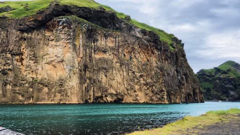 Vibrant-turquoise-Heimaklettur-cliff-idyllic-secluded-Icelandic-mountain-cove
