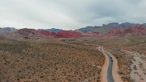 Aerial-drone-shot-of-a-desert-highway-with-scenic-mountains-in-the-background
