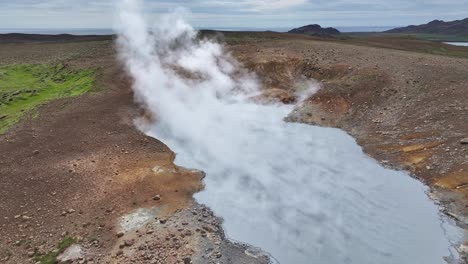 An-aerial-drone's-forward-view-of-Engjahver's-steam-lake-on-the-Reykjanes-Peninsula-in-Iceland,-hovering-just-above-the-steam