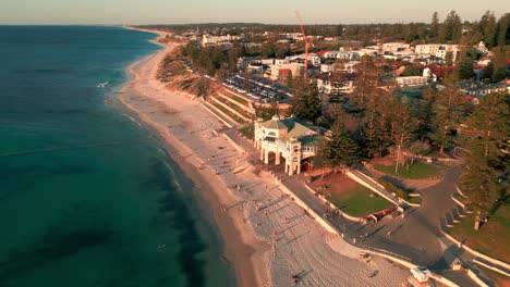 Approaching-Aerial-over-Cottesloe-Beach-and-Indiana-Teahouse-at-Sunset,-Perth,-Australia