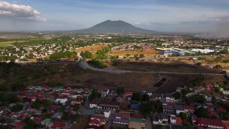 Drone-panorama-of-rural-Asian-neighborhood,-approaching-highway-and-giant-mountain-in-background