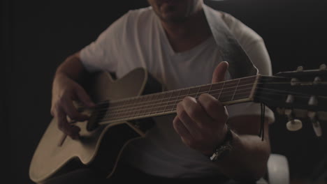 Man-playing-and-performing-on-an-Acoustic-guitar-with-black-background-and-soft-warm-light