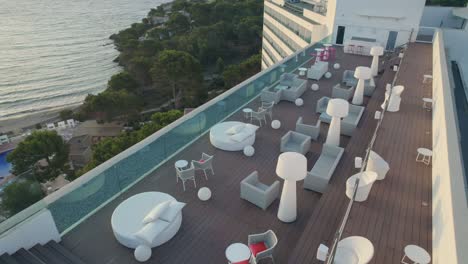 Drone-hovers-over-the-hotel's-terrace,-lifts,-reveals-Balearic-sea