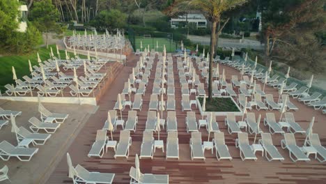 Drone-uncovering-numerous-sun-loungers-at-a-beautiful-hotel-with-pools-in-Palma-Mallorca,-Spain