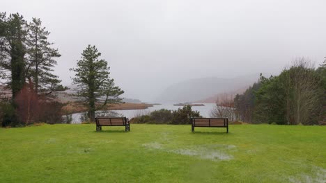Benches-on-green-grass-overlooking-misty-lake-landscape-in-Ireland