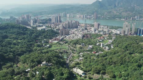 Zhuwei-district-in-Taipei-with-urban-skyline-and-greenery,-river-in-background,-Aerial