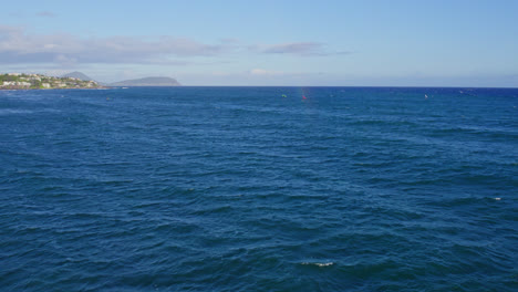 Drohnenaufnahmen-Des-Königsblauen-Wassers-Des-Pazifischen-Ozeans,-übersät-Mit-Kiteboardern-Und-Surfern,-Die-Das-Schöne-Wetter-In-Hawaii-Genießen