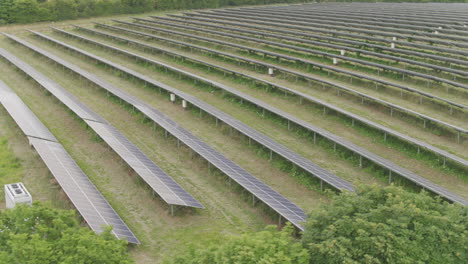 Luftvorbeiflug-Einer-Großen-Solarpanelfarm-Zwischen-Grünen-Englischen-Feldern-Und-Bäumen-Auf-Dem-Land