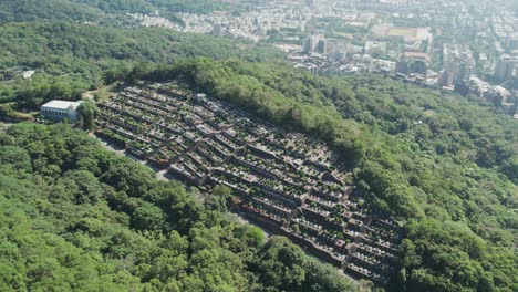 A-traditional-Taiwanese-cemetery-nestled-in-lush-greenery-with-Taipei-in-the-background,-Aerial