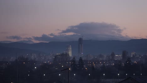 Time-Lapse-of-a-city-skyline-with-a-mountain-behind-it,-at-dusk