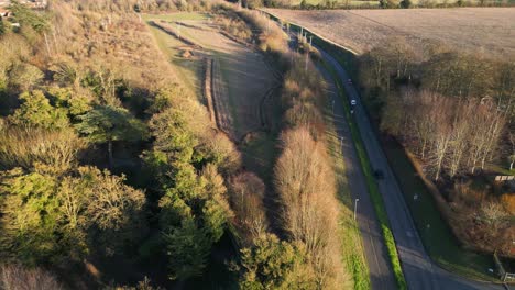 Bury-st-edmunds-showing-roads-curving-through-autumnal-trees,-cars,-and-fields-at-golden-hour,-aerial-view