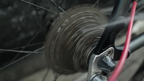 Closeup:-Bicycle-mechanic-sprays-cleaner-on-rear-cassette-bike-gears