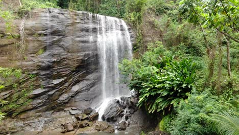 Woman-watching-tropical-waterfall,-tourist-sightseeing-aerial