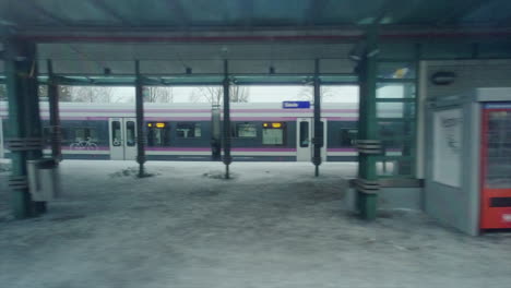 Helsinki-public-transit-train-departs-station-platform-in-winter-snow