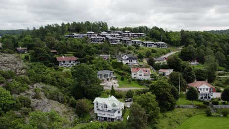 Tiered-houses-built-up-along-rocky-hillside-and-forest-in-Ljungskile,-Bohuslan,-Sweden,-Aerial