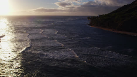 drone-footage-of-the-rolling-waves-of-the-Pacific-ocean-ripple-towards-the-island-coast-of-Oahu-Hawaii-near-Honolulu-as-the-sun-reflects-off-the-water