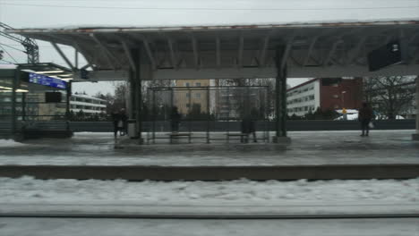 Winter-city-train-pulls-into-snowy-station-platform-on-cold-grey-day