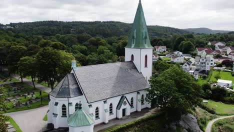 Ljungs-Kyrka-with-surrounding-greenery-and-residential-area-in-Ljungskile,-Sweden,-aerial-view